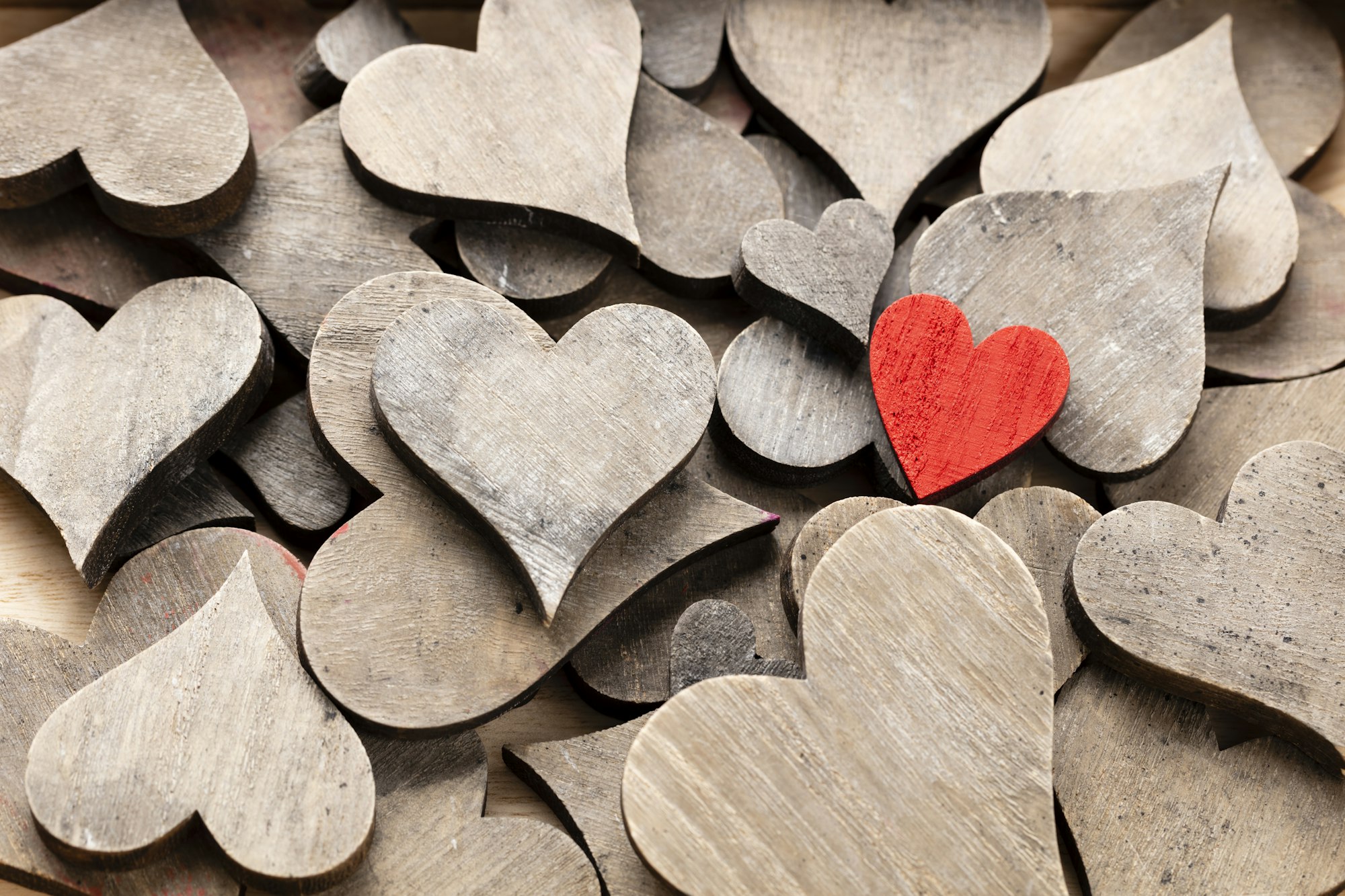 Wooden hearts, one red heart on the heart background.